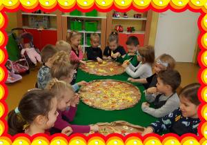 Dzieci siedzą przy stole. Przed nimi wykonane pizze.